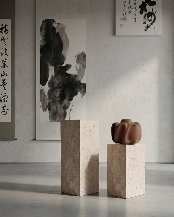 Ceramic vase on a limestone podium in a minimalistic room with abstract art.