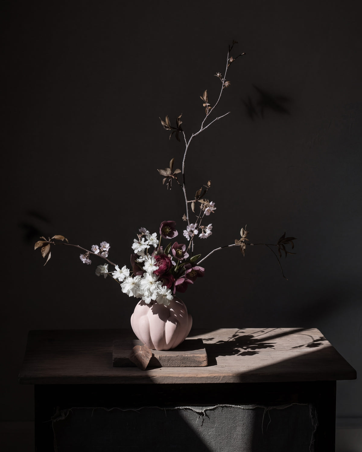 A Bloom Vase with flowers on a dark surface against a dark background