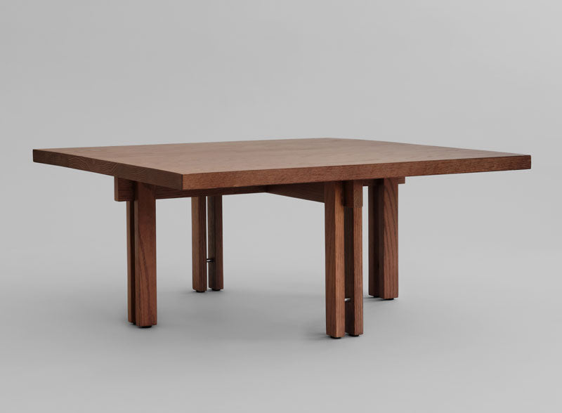 A square Plinth coffee table with a medium brown finish and blocky, mid-century modern legs, shown on a neutral gray background.